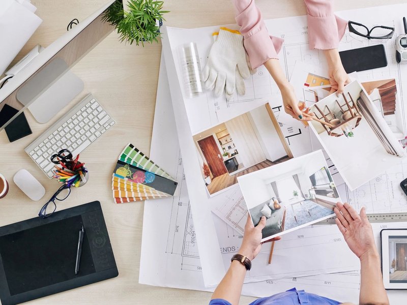 two pair of hands working on a desk with plans and documents - bdflooringinc